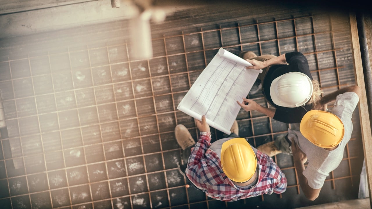 Professionnels du bâtiment qui regardent un plan de construction.